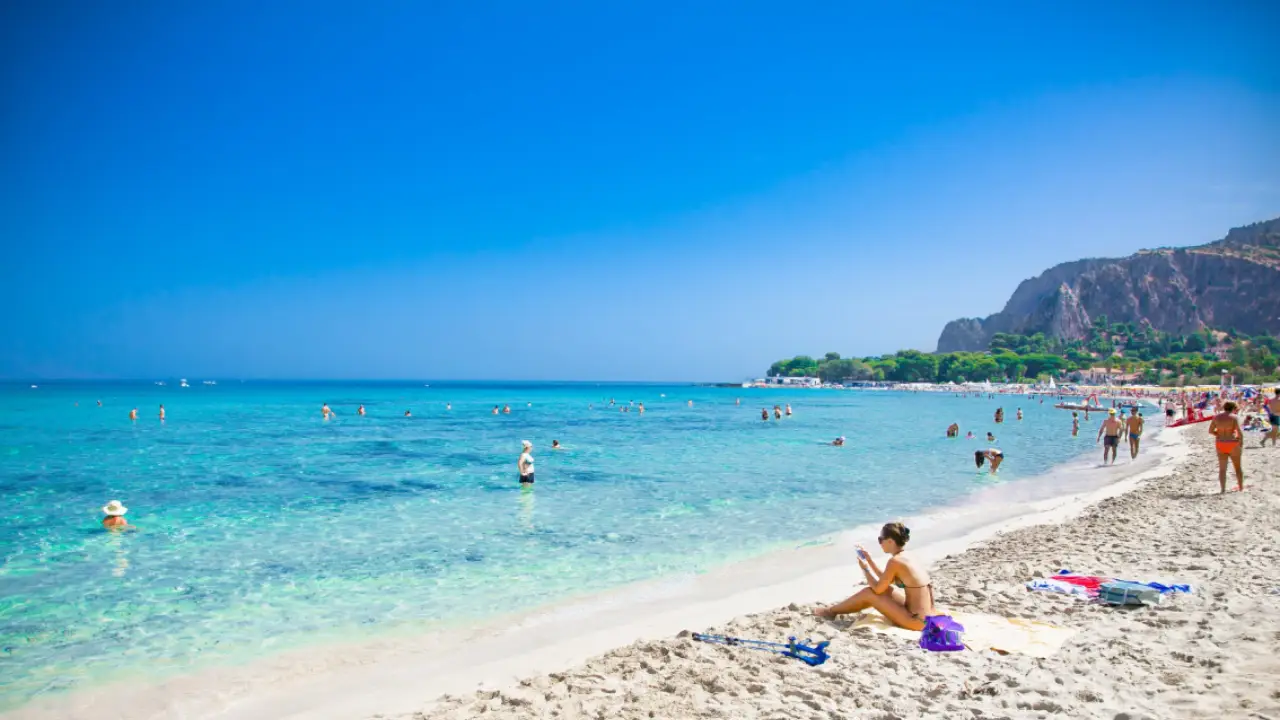 Blick auf das Meer von Mondello in Palermo mit Menschen, die im Wasser baden